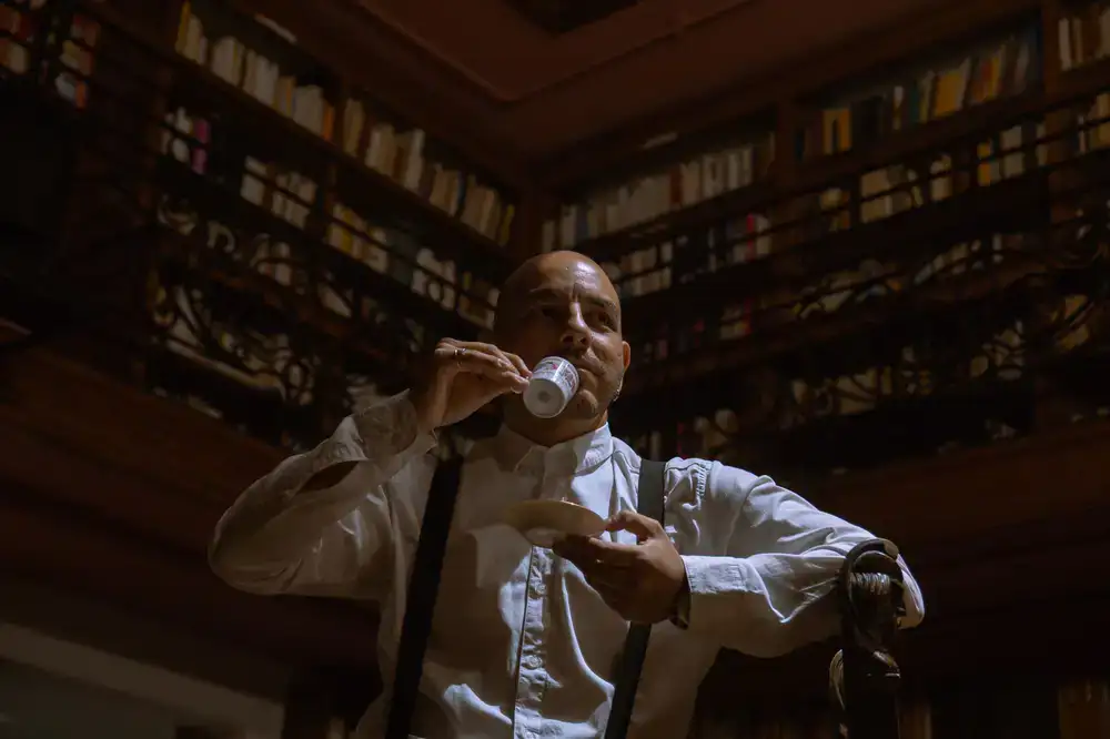 Actors in vintage attire standing in a grand dimly lit library